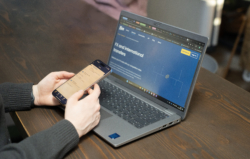 A person sitting at a desk with a smartphone in hand, while Fire’s website is open on a laptop screen displaying the “FX and international transfers” page. The image highlights Fire’s international payments solutions.