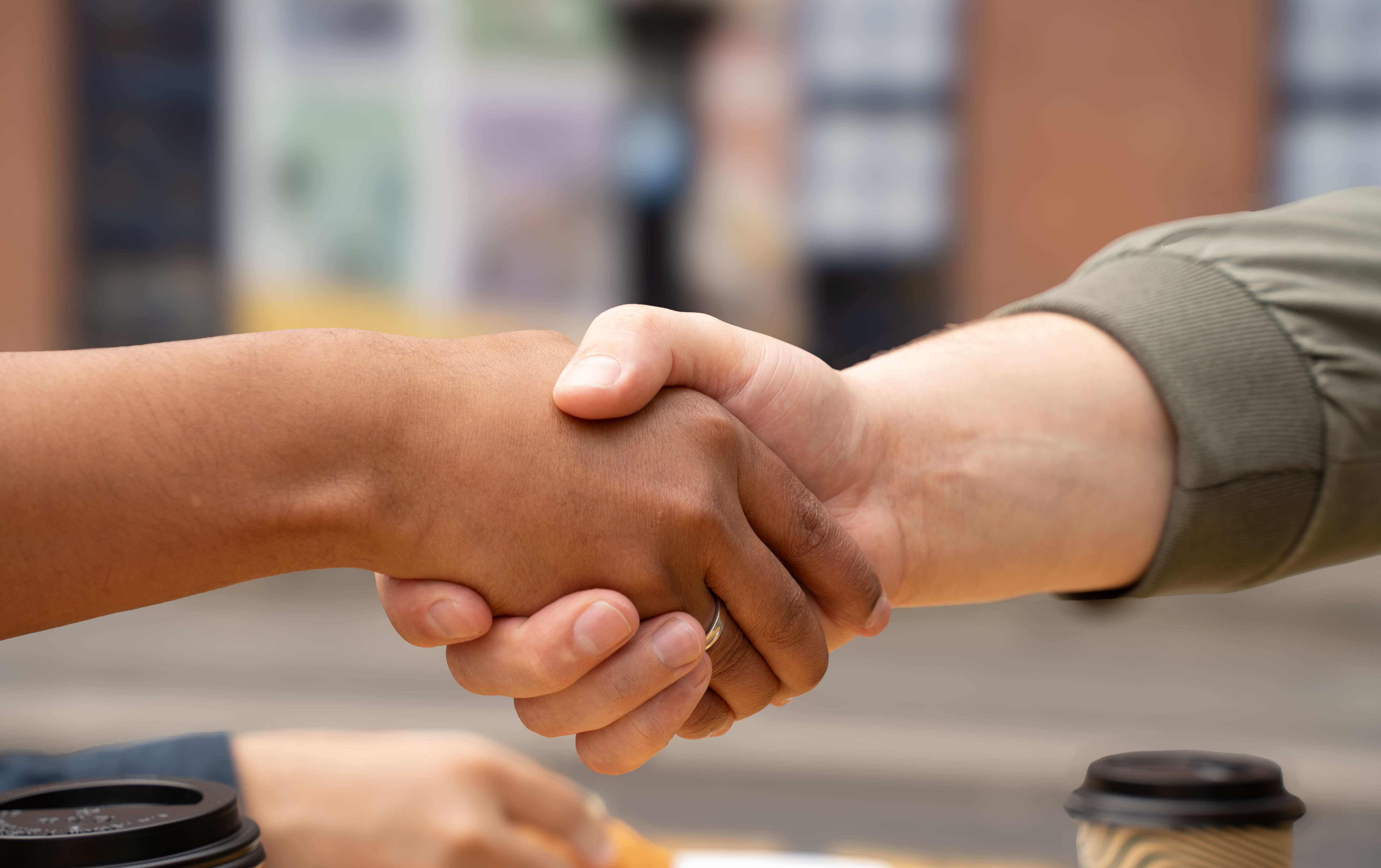 Two people shaking hands in an outdoor setting.