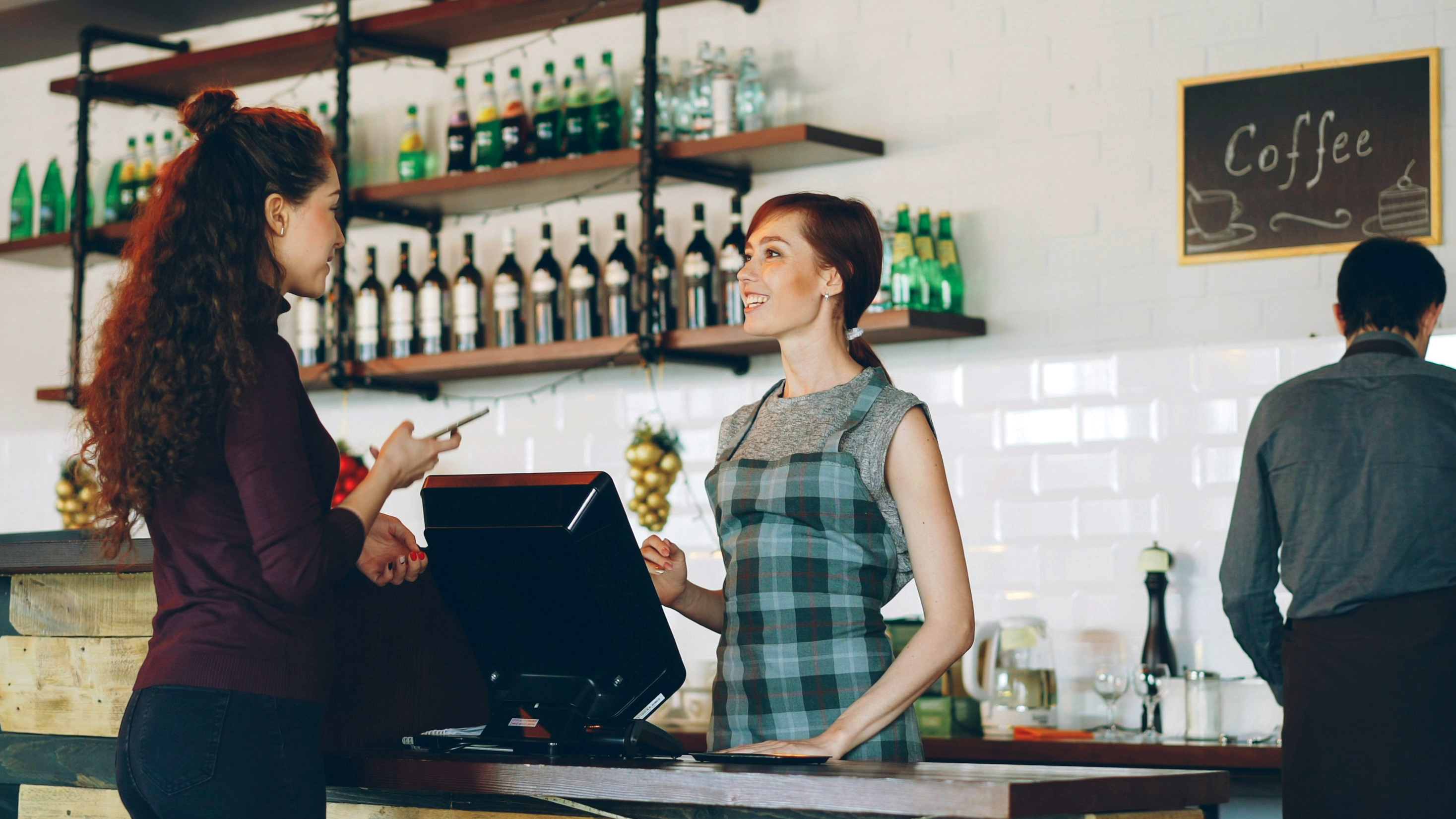 Customer at a café making a payment, barista facilitating via open banking.