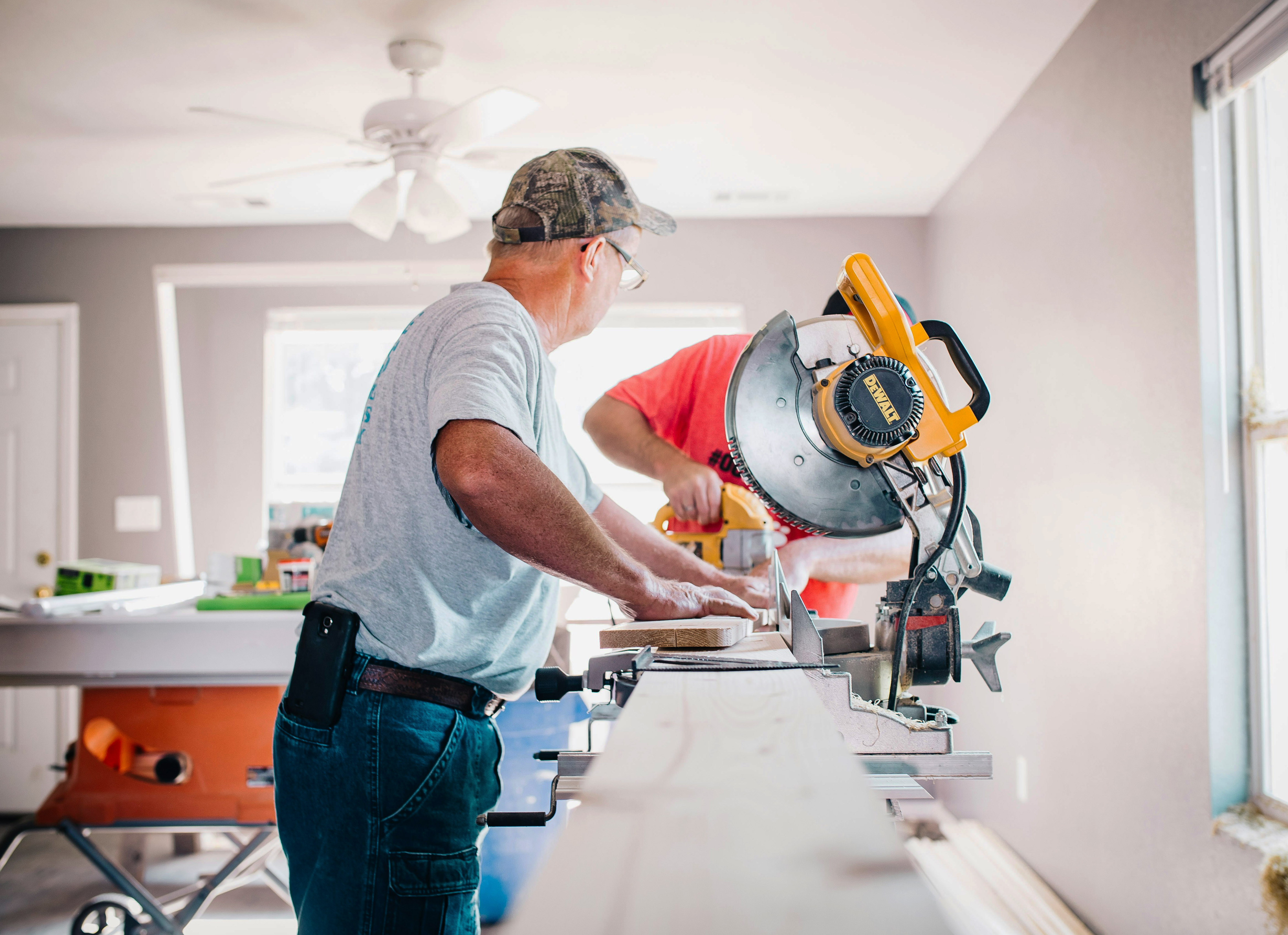 Two workers cutting wood with a circular saw indoors.